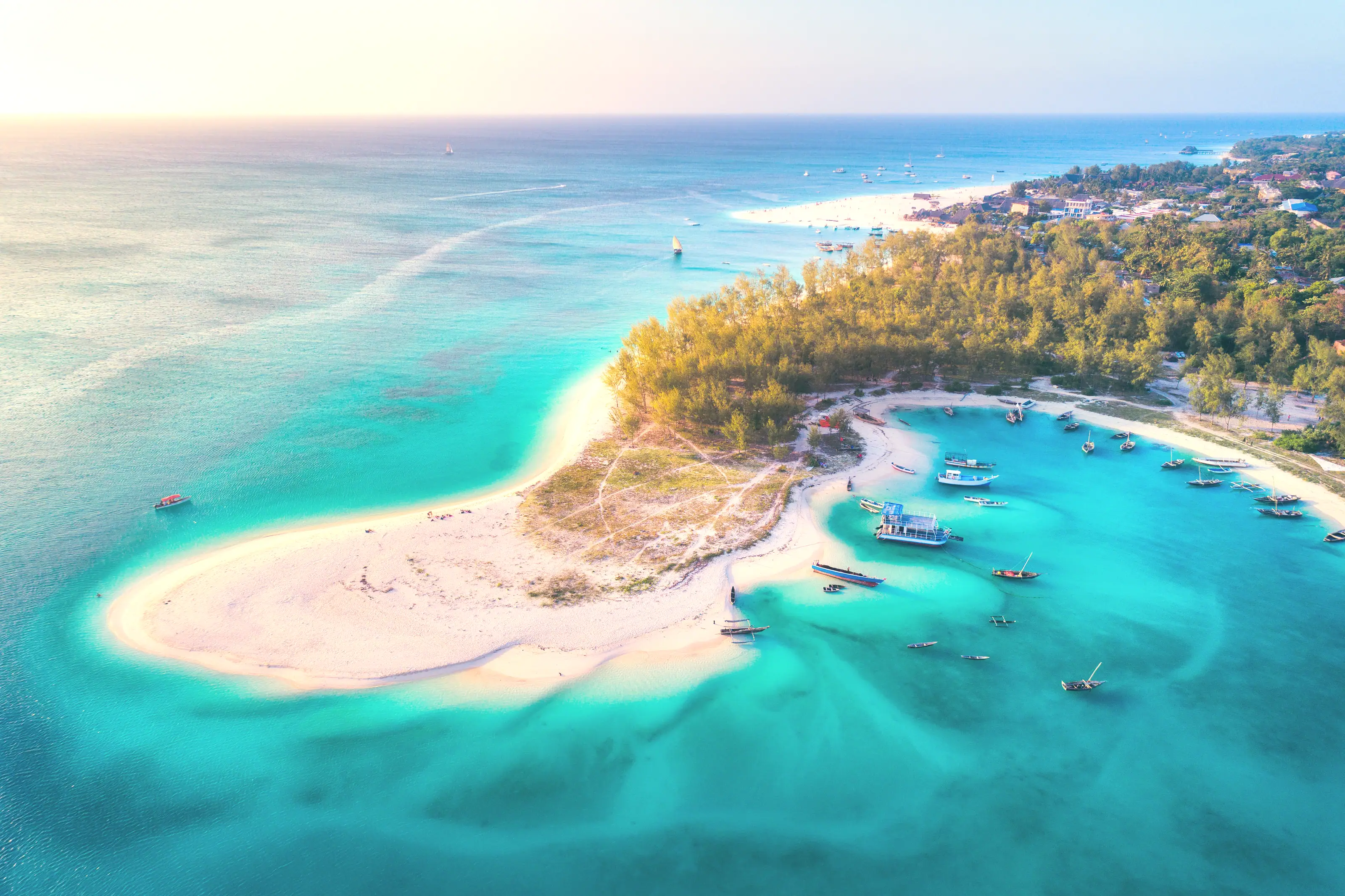 An aerial view of a sandbar and fishing boats moored in shallow reef water