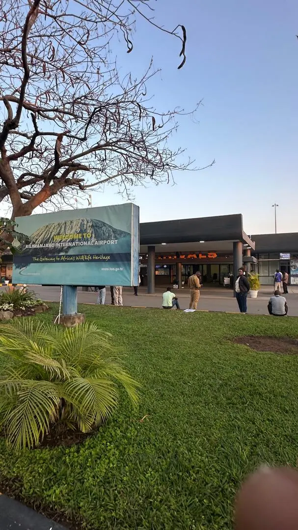 The walkway to an airport terminal past a lawn and garden