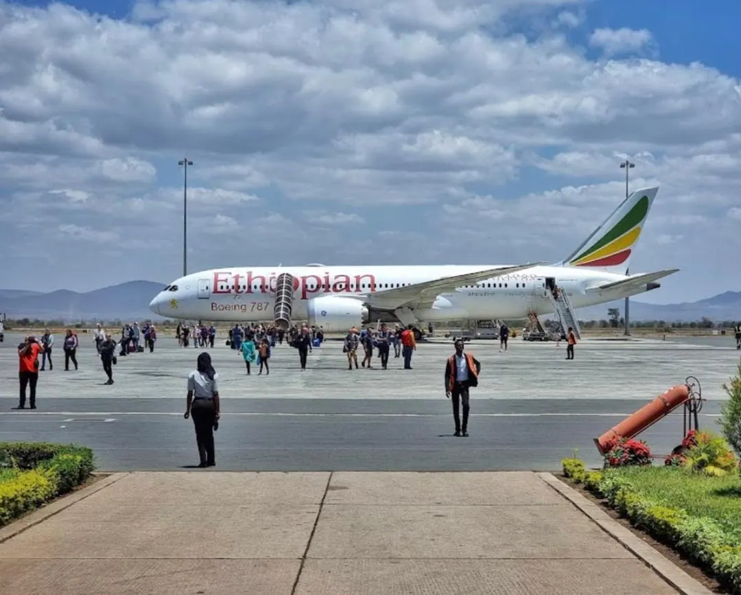 An Ethiopian Airlines aircraft on the apron with passengers walking across to the terminal