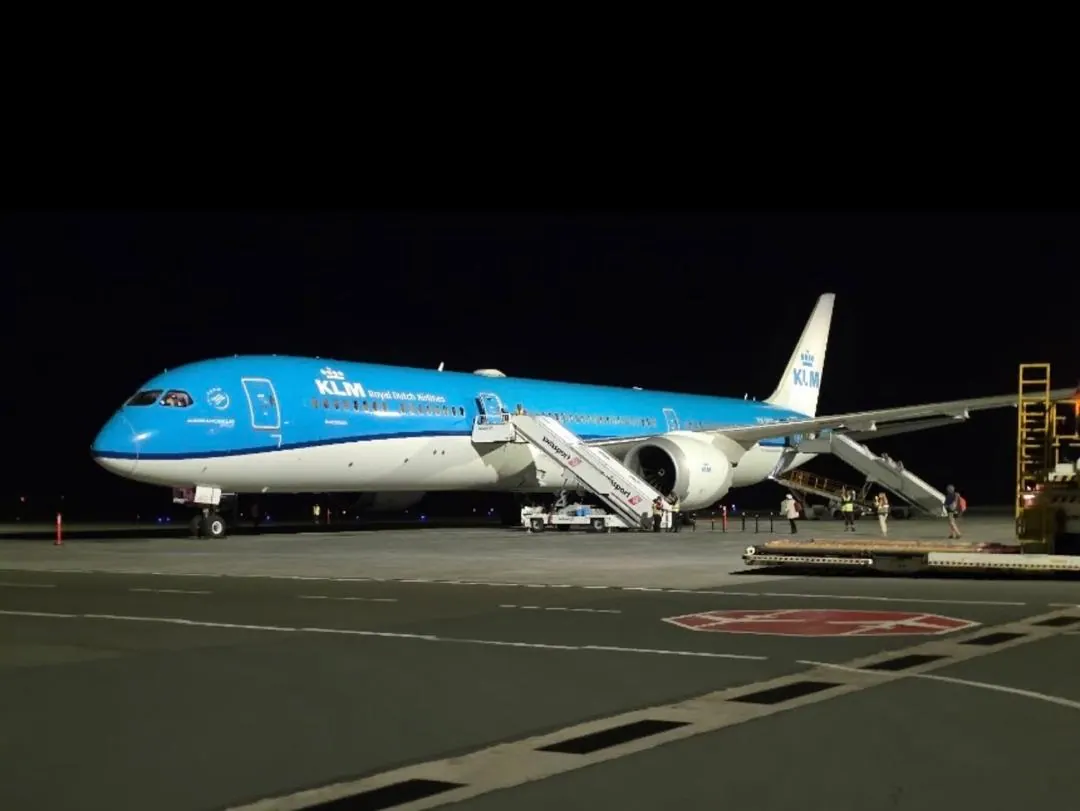 A KLM aircraft on its stand at night with the air stairs attached