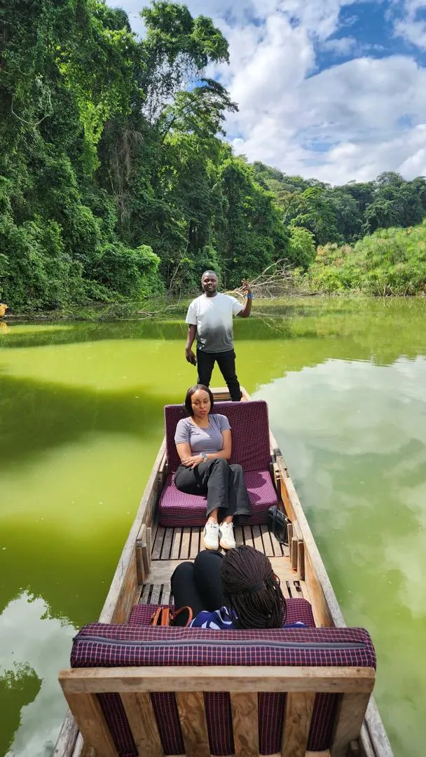 Guests seated in a canoe on Lake Duluti, the guide standing at the bow