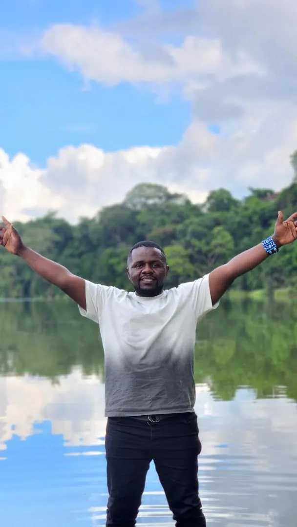 A guide standing in the shallows of Lake Duluti with his arms spread wide