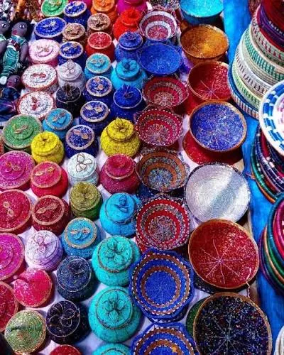 Stacks of brightly beaded bowls and baskets on a market stall