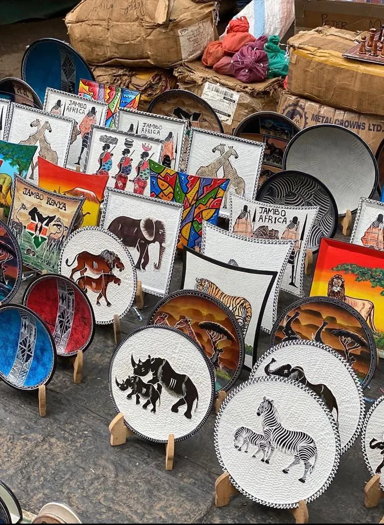 Painted plates and bowls on wooden stands: rhino, zebra, elephant and Maasai figures