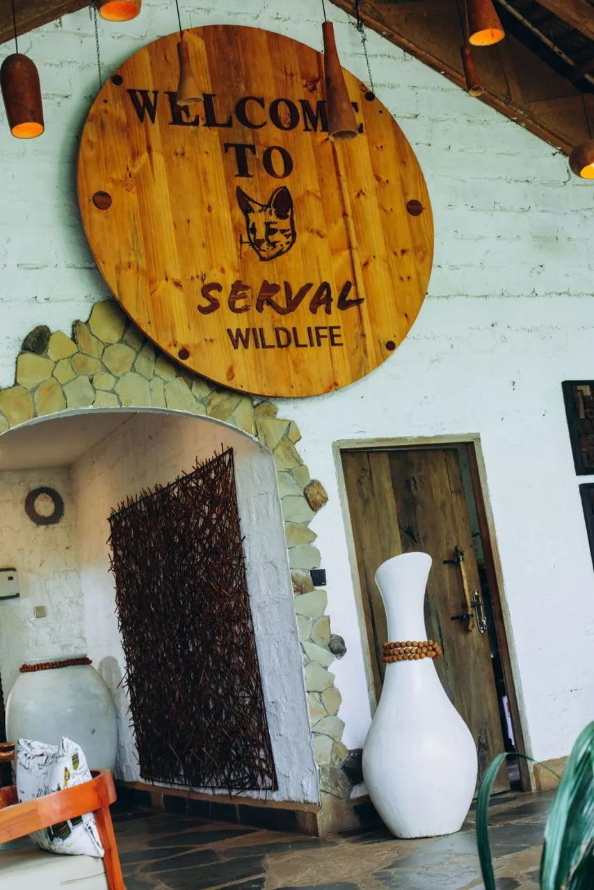 The round wooden Welcome to Serval Wildlife sign above the sanctuary's entrance