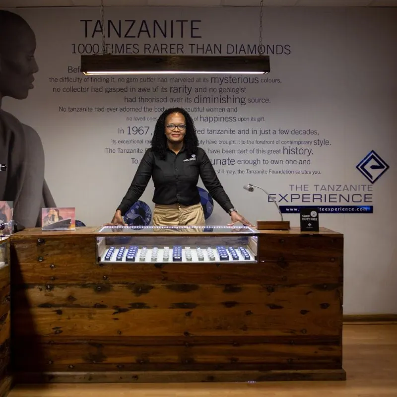 A member of staff behind a display of tanzanite stones at The Tanzanite Experience counter